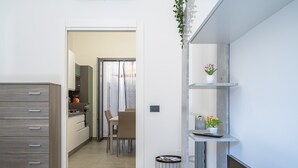 A modern kitchen with a dining area, a small round table with a magazine, and a potted plant on a shelf. - Apartment "Erre House" with Private Terrace & Wi-Fi (Avola)