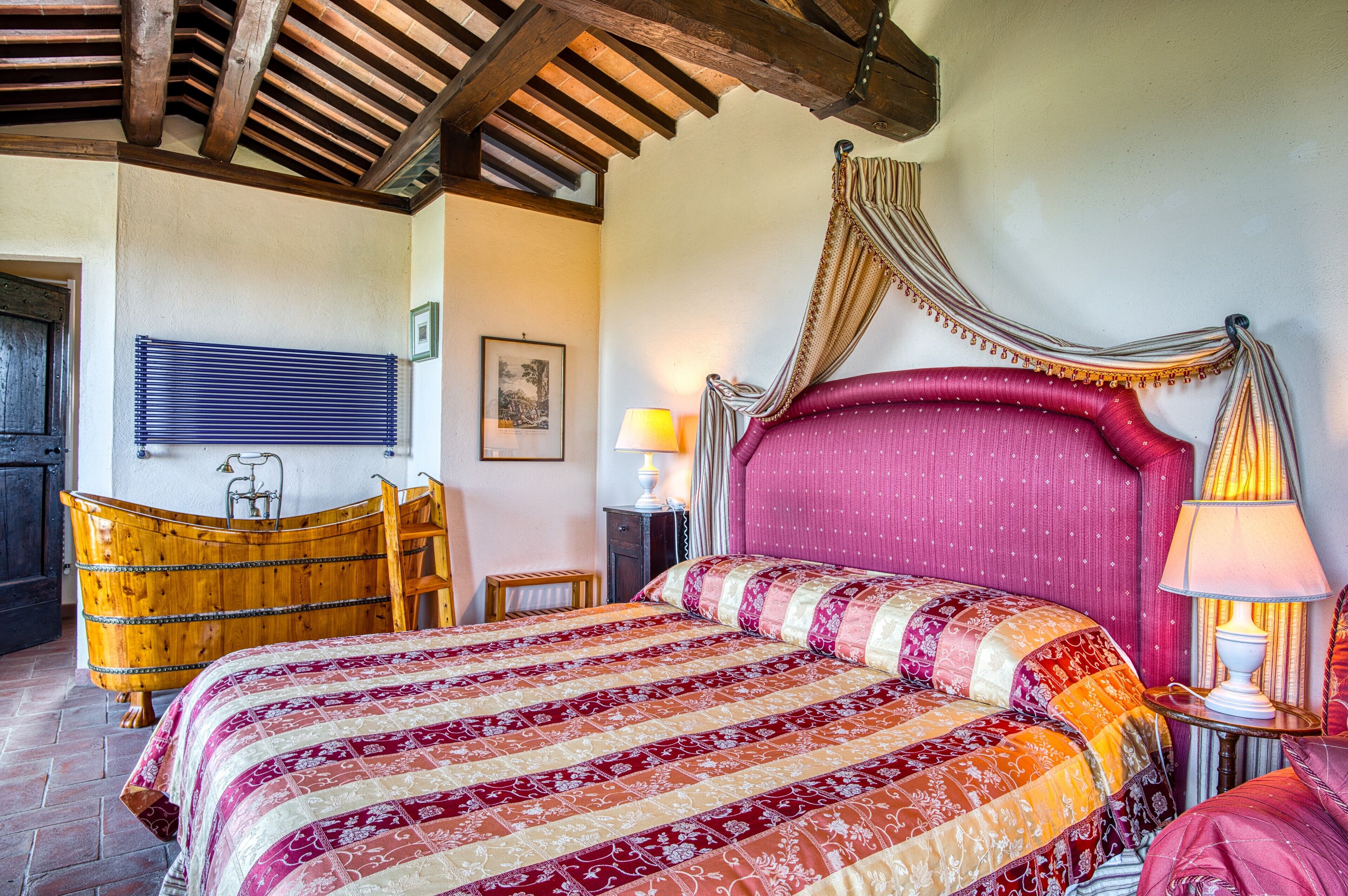 A bedroom with a large bed, wooden headboard, a wooden bathtub, and a wooden chair.