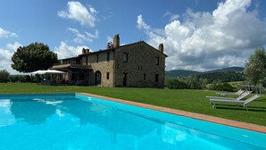 A stone building with a swimming pool, a covered patio, and a grassy lawn. - Villa 'Le Buccole Country House' con vista sulle colline perugine, Wi-Fi e aria condizionata. (Marsciano)