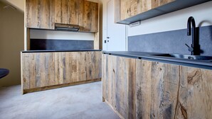 Een keuken met houten kastjes, een zwart aanrecht en een RVS spoelbak.
