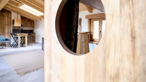 A wooden interior with a circular opening, a kitchen area, and a dining space. - Apartment in Luxury Chalet “Baita Treeb Breva” with Lake View & Wi-Fi - Civenna (Bellagio) (Bellagio)