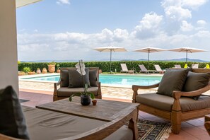 Uma área na piscina com espreguiçadeiras, guarda-sóis e vista para a piscina.