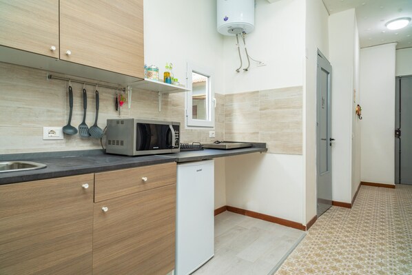 Une cuisine moderne avec des meubles en bois, un four à micro-ondes encastré et un chauffe-eau.