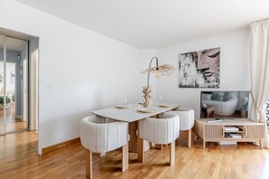 Una sala de estar moderna con una mesa de comedor, sillas, un televisor y obras de arte en la pared.