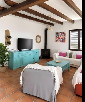 Una sala de estar con televisión, sofá y chimenea.