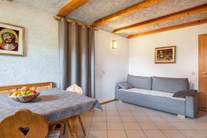 A room with a dining table, a sofa, a wooden ceiling, and a framed picture on the wall.