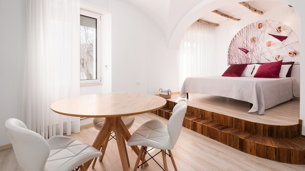 A modern bedroom with a bed, a dining table, and chairs.