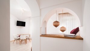 A modern interior with a dining area, a TV mounted on the wall, and a window with a view.