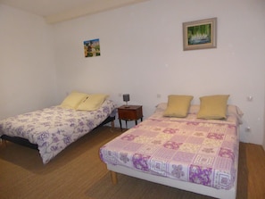 Un dormitorio con dos camas individuales, una mesita de noche pequeña y un cuadro colgado en la pared.