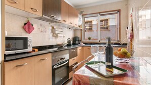 Une cuisine moderne avec des meubles en bois, un four à micro-ondes, un four traditionnel et un coin repas avec une table dressée pour deux personnes.