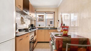 Une cuisine avec des meubles de rangement en bois, une fenêtre et une table recouverte d’une nappe.