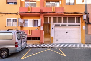 A building with a garage door, a parked van, and a staircase leading to an entrance.