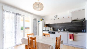 A modern kitchen with white cabinets, a black countertop, and a dining area with a table and chairs.