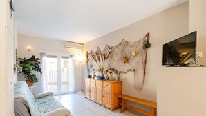 A living room with a sofa, a wooden bench, a TV, and a decorative wall hanging.