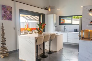 Eine moderne Küche mit einer zentralen Kochinsel, Barhocker, einer Spüle und einem Fenster mit Blick.