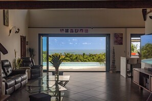 A modern living room with a glass table, leather sofas, and a view of the ocean. - A 5min de la Plage-villa Avec vue mer Magnifique-salle de Jeux-piscine-jacuzzi (Sainte-Rose)