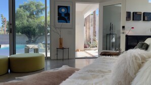 A modern living room with a large glass door leading to an outdoor area, a fireplace, and a minimalist decor style.