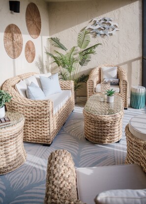 A wicker furniture set with cushions, a glass coffee table, and a potted plant. - Loggerhead Cay 433 NEWLY renovated and gorgeous! (Sanibel)