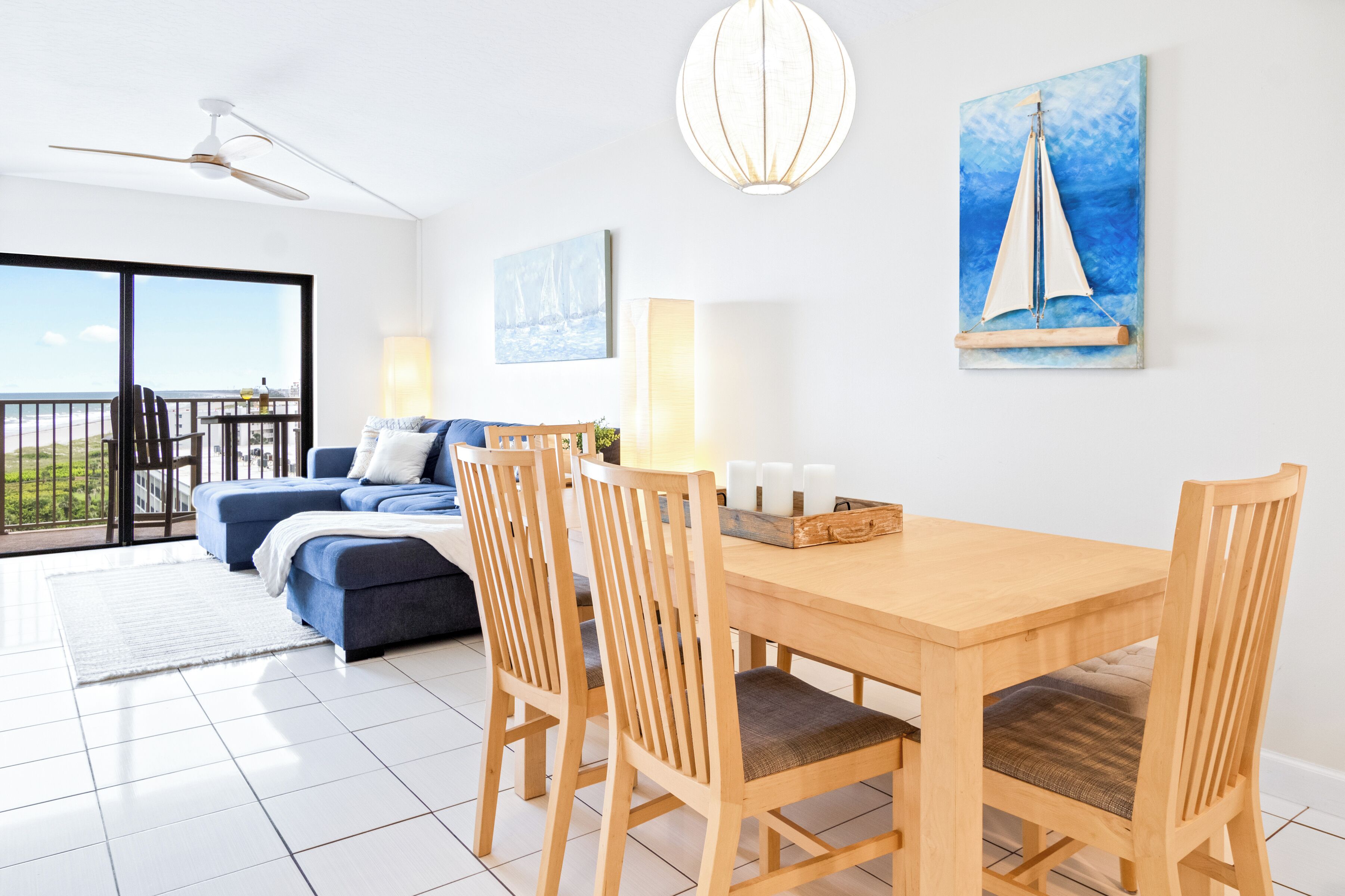 Uma sala de estar moderna com uma mesa de jantar de madeira, duas cadeiras de madeira, um sofá e uma varanda com vista.