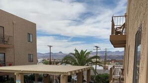 A pool area with lounge chairs, a covered patio, and a view of mountains. - 1st Floor Condo in the Desert w/ Pool, Spa & BBQ (Lake Havasu City)