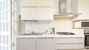 A kitchen with white cabinets, a gas stove, a microwave, and a sink. - GuestHost - Large and bright apartment that can accommodate up to 5 people with 2 bedrooms and 2 bathrooms, which boasts a beautiful view of the Villa di Sant'Antonio and, in the distance, of the sea from the balcony and window. Located a few steps from  (Monopoli)