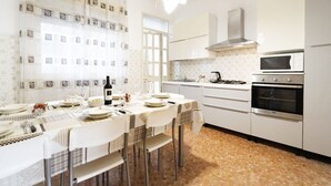A kitchen with white cabinets, a microwave, an oven, and a dining table set with plates and glasses. - GuestHost - Large and bright apartment that can accommodate up to 5 people with 2 bedrooms and 2 bathrooms, which boasts a beautiful view of the Villa di Sant'Antonio and, in the distance, of the sea from the balcony and window. Located a few steps from  (Monopoli)