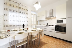 A kitchen with white cabinets, a microwave, an oven, and a dining table set with plates and glasses.