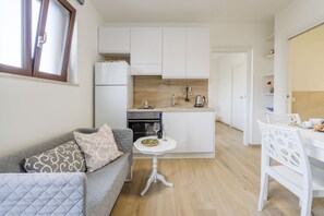 A compact kitchen with white cabinets, a dining table, and a small white table.
