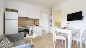 A compact living space with a kitchenette, dining area, and a TV mounted on the wall.
