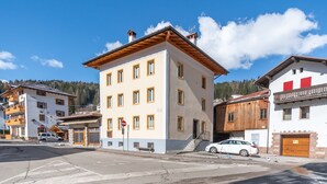 A multi-story building with a flat roof and a balcony on the second floor. - Casa Caviola Centro (Falcade)