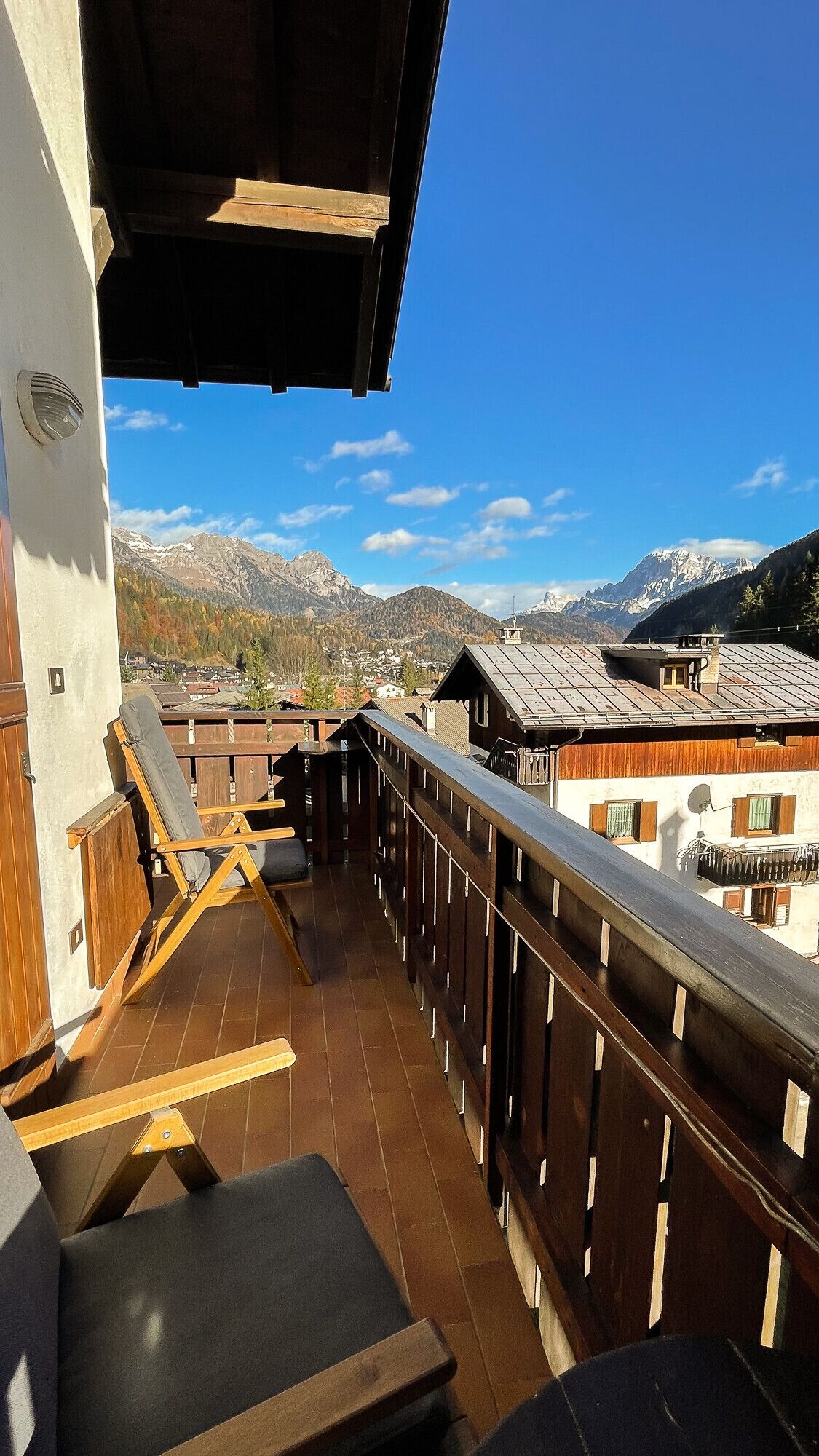 Ein Balkon mit Holzgeländern, einem Stuhl und einem Tisch.
