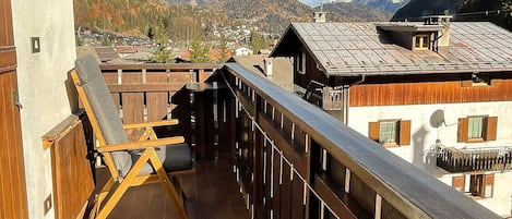A balcony with wooden railings, a chair, and a table.