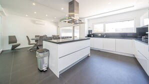 Een moderne keuken met witte kasten, een centraal eiland en een groot raam voor natuurlijk licht.