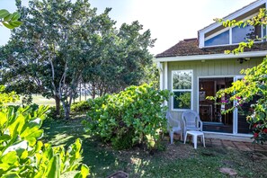 A house with a small porch, a chair, and a garden with various plants and trees. - Kuilima Estates | Golf View 2 BR | Car Incl. w/ 6+ Nights | KUL-E113 by KBM (Kahuku)