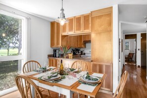Uma cozinha moderna com armários de madeira e uma área de jantar preparada para seis pessoas.
