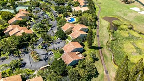 An aerial view of a residential area with houses, a swimming pool, and a golf course. - Kuilima Estates | Golf View 2 BR | Car Incl. w/ 6+ Nights | KUL-E113 by KBM (Kahuku)