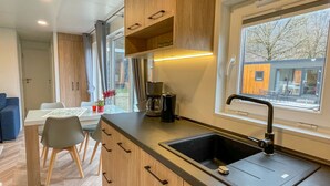 A modern kitchen with wooden cabinets, a black sink, and a window with a view of the outside. - Villa Ramses by Interhome (Riedenburg)