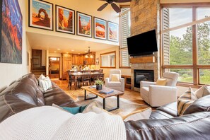 Un salón amplio con chimenea, un televisor grande montado en la pared y un comedor con muebles de madera.