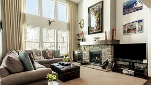 Ein Wohnzimmer mit Kamin, einer Sofagarnitur, einem Fernseher und Kunstwerken an den Wänden.