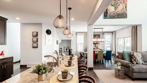 Eine moderne Küche mit Granit-Arbeitsplatte, Pendelleuchten und einem Essbereich mit Stühlen und Tisch.