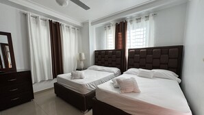 A hotel room with two beds, a dresser, a mirror, and a ceiling fan.