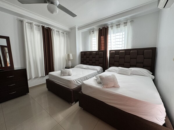 Habitación de hotel con dos camas, un aparador, un espejo y un ventilador de techo.