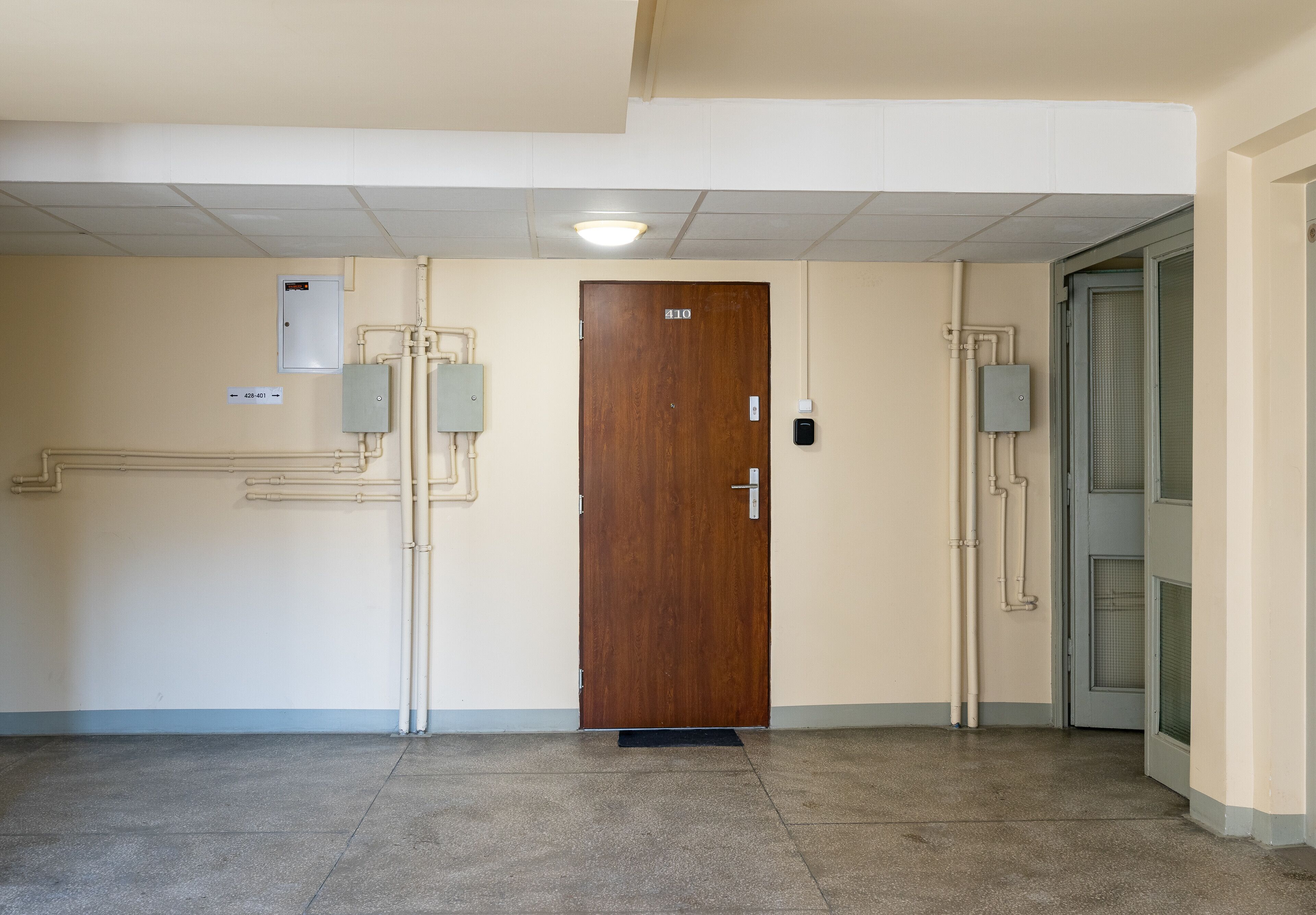 A hallway with a wooden door marked 310, a light fixture, and a doorbell.
