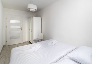 A hotel room with a bed, a chair, a wardrobe, and a door.