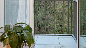 A balcony with a metal railing, a potted plant, and a view of trees and sky. - Nadolnik Apartment with Mezzanine (Poznan)