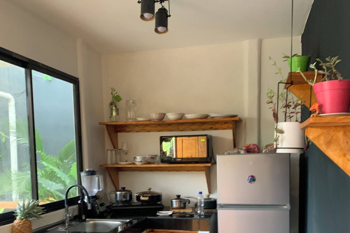 A compact kitchen with a refrigerator, stove, and wooden cabinets.
