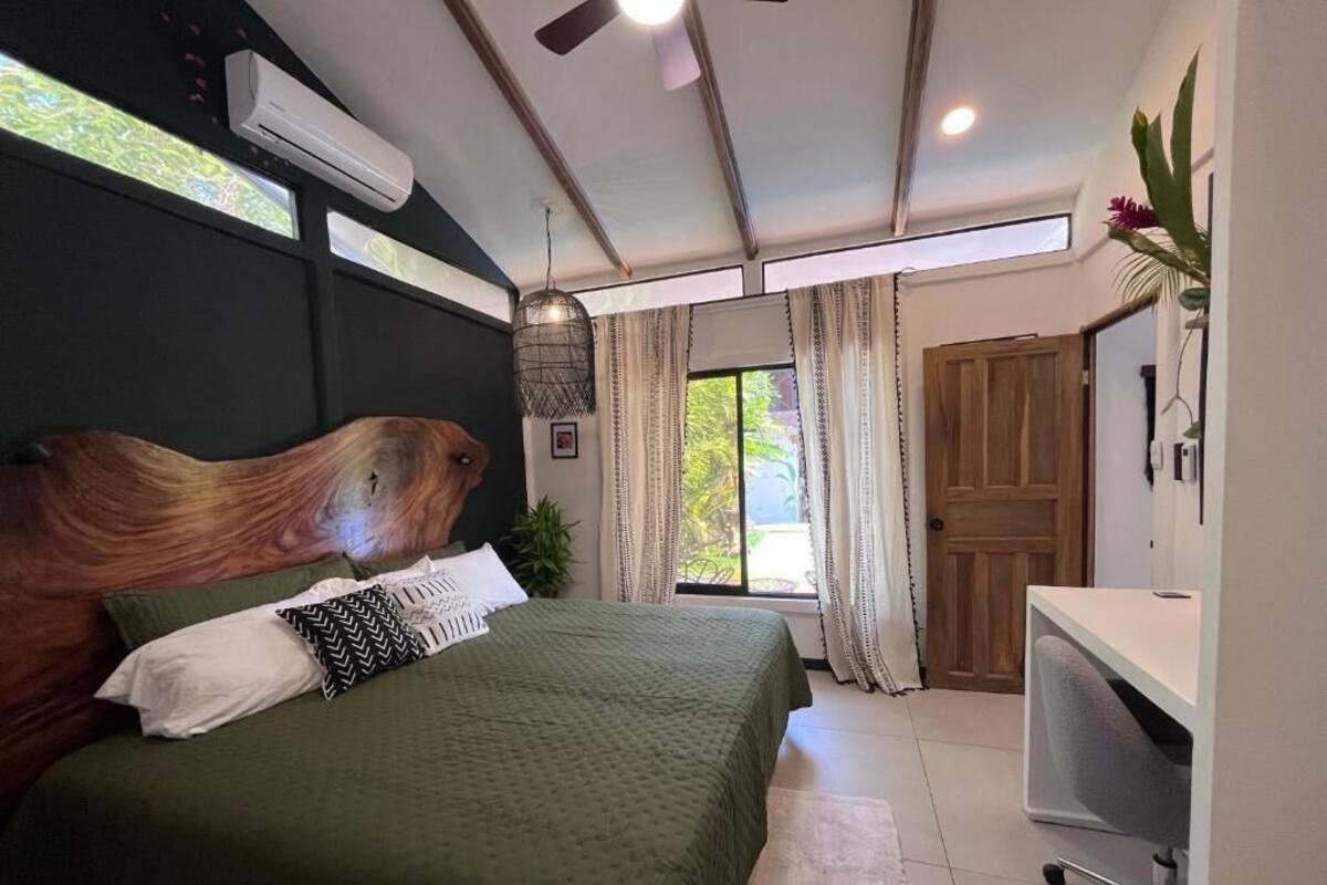 A bedroom with a bed, a desk, and a large window.