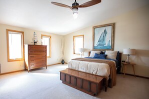 A bedroom with a bed, dresser, bench, ceiling fan, and a painting on the wall. - Spacious light-filled house near Stillwater - The Stone's Throw Riverhouse (Stillwater)