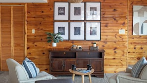 Una sala de estar con una pared de madera, un sofá, una mesa de centro y cuadros enmarcados.