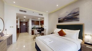 Ein Hotelzimmer mit einem großen Bett, einem Schreibtisch, einem Stuhl und Blick auf den Flur.